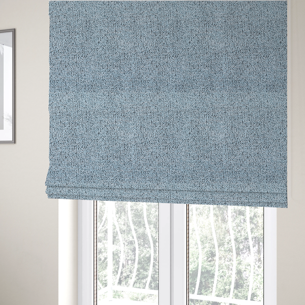 The fabric used to create these Roman blinds is a light blue textured fabric with a dense, irregular black speckled pattern.