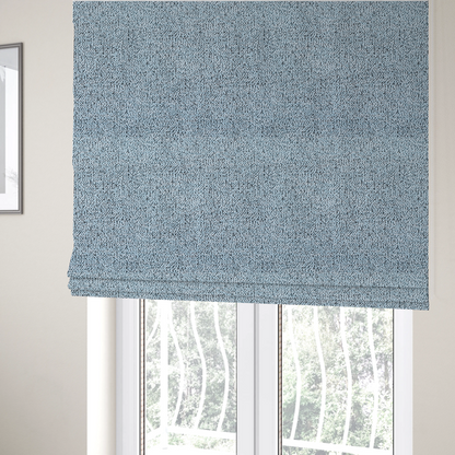 The fabric used to create these Roman blinds is a light blue textured fabric with a dense, irregular black speckled pattern.