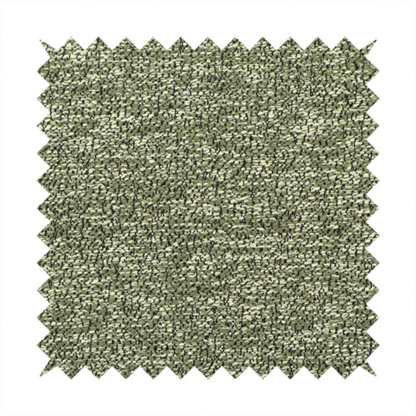 A sage green textured fabric with a dense, irregular black speckled pattern.
