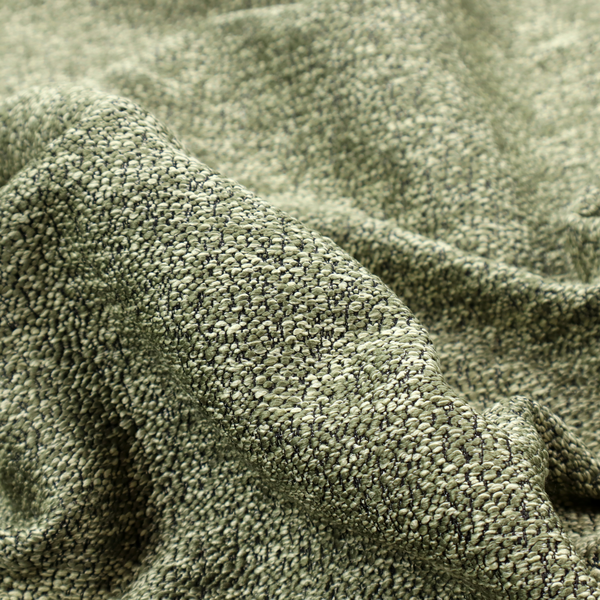A sage green textured fabric with a dense, irregular black speckled pattern.