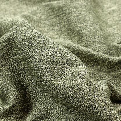 A sage green textured fabric with a dense, irregular black speckled pattern.