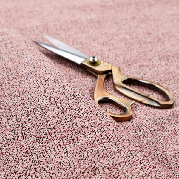 A dusty rose textured fabric with a dense, irregular black speckled pattern.