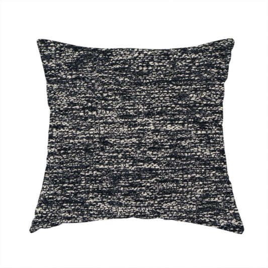 The fabric used to create this handmade cushion is a black textured fabric with a dense, irregular cream and grey speckled pattern.