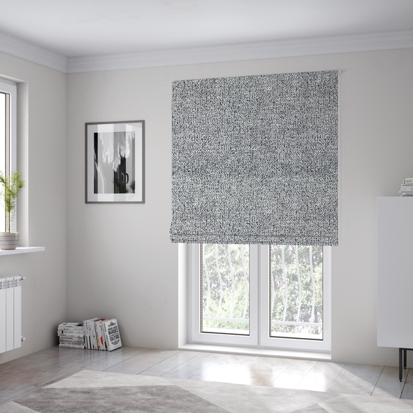 The fabric used to create these Roman blinds is a light grey or silver textured fabric with an integrated black speckled motif, creating a cool-toned, high-contrast pebbled appearance.
