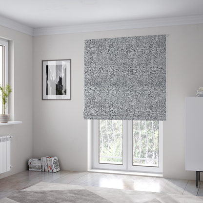 The fabric used to create these Roman blinds is a light grey or silver textured fabric with an integrated black speckled motif, creating a cool-toned, high-contrast pebbled appearance.