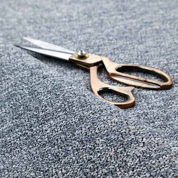 A silver-grey textured fabric with a dense, irregular black speckled pattern.