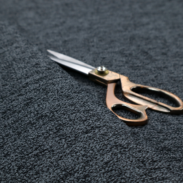 A charcoal grey textured fabric with a dense black speckled pattern, creating a dark, moody salt-and-pepper effect with a heavy pebbled weave.