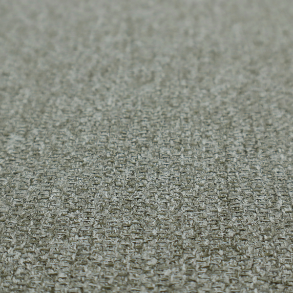 A textured woven upholstery fabric. The material features a dense, multi-tonal weave of sage green, grey, and beige threads, creating a speckled effect with a tactile, matte finish.