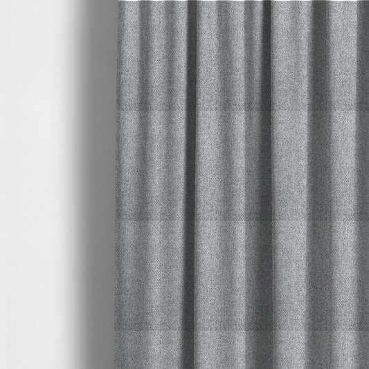 The fabric used to create these made-to-measure curtains is a weathered fabric blends charcoal and slate yarns with cool silver and off-white threads, resulting in a balanced, stony neutral that offers a modern and professional aesthetic.