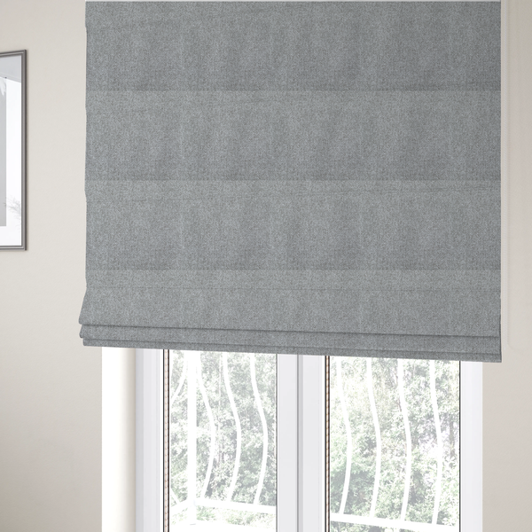 The fabric used to create these Roman blinds is a weathered fabric blends charcoal and slate yarns with cool silver and off-white threads, resulting in a balanced, stony neutral that offers a modern and professional aesthetic.