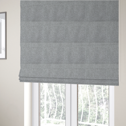 The fabric used to create these Roman blinds is a weathered fabric blends charcoal and slate yarns with cool silver and off-white threads, resulting in a balanced, stony neutral that offers a modern and professional aesthetic.