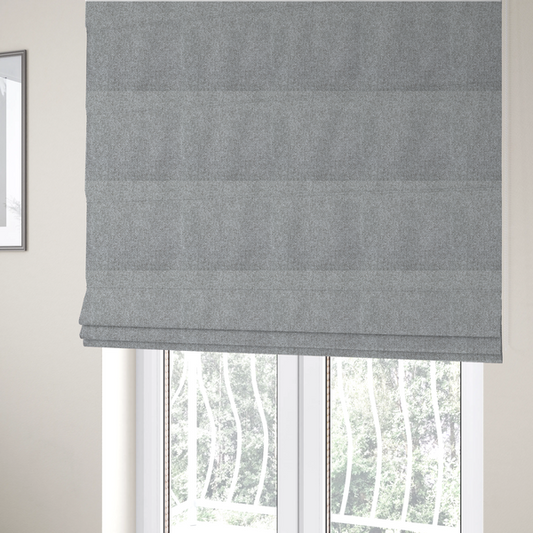 The fabric used to create these Roman blinds is a weathered fabric blends charcoal and slate yarns with cool silver and off-white threads, resulting in a balanced, stony neutral that offers a modern and professional aesthetic.