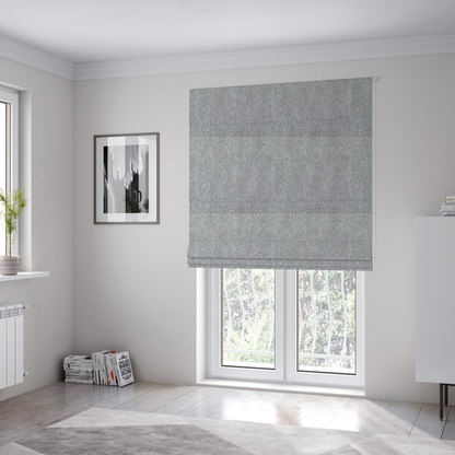 The fabric used to create these Roman blinds is a weathered fabric blends charcoal and slate yarns with cool silver and off-white threads, resulting in a balanced, stony neutral that offers a modern and professional aesthetic.