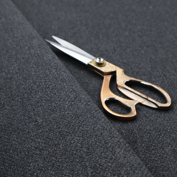 A deep, obsidian Black. Unlike a flat solid, this fabric uses a dense basket weave to create a rich, textured surface. The interlacing yarns catch the light in a way that provides a soft charcoal sheen, adding depth to the dark palette.