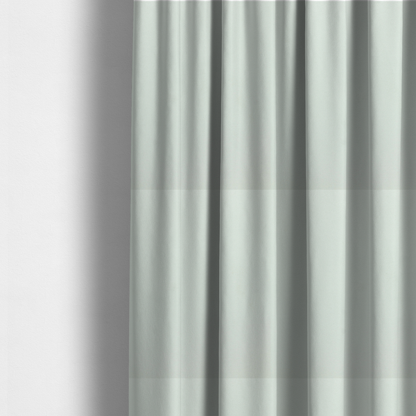 The fabric used to create these made-to-measure curtains features a dense, plush pile with a soft matte finish in a very pale, cool-toned minty blue. This high-performance upholstery material offers a luxurious feel and a specialized water-resistant coating for superior durability and a serene, modern aesthetic.
