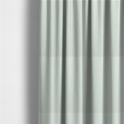 The fabric used to create these made-to-measure curtains features a dense, plush pile with a soft matte finish in a very pale, cool-toned minty blue. This high-performance upholstery material offers a luxurious feel and a specialized water-resistant coating for superior durability and a serene, modern aesthetic.