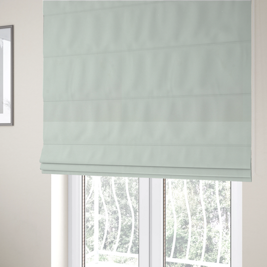 The fabric used to create these Roman blinds features a dense, plush pile with a soft matte finish in a very pale, cool-toned minty blue. This high-performance upholstery material offers a luxurious feel and a specialized water-resistant coating for superior durability and a serene, modern aesthetic.
