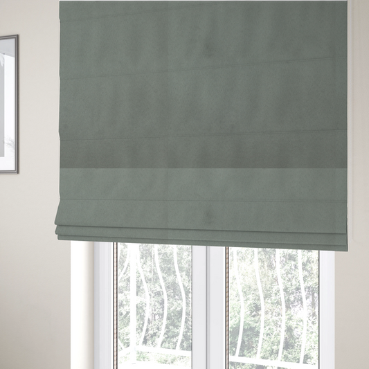 The fabric used to create these Roman blinds features a dense, plush pile with a soft matte finish in a sophisticated, muted earthy green. This high-performance upholstery material offers a luxurious feel and a specialized water-resistant coating for enhanced durability and a natural, calming aesthetic.