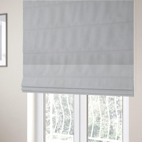 The fabric used to create these Roman blinds features a dense, plush pile with a soft matte finish in a bright, clean light grey. This high-performance upholstery material offers a luxurious texture and a specialized water-resistant coating for a modern, durable aesthetic.