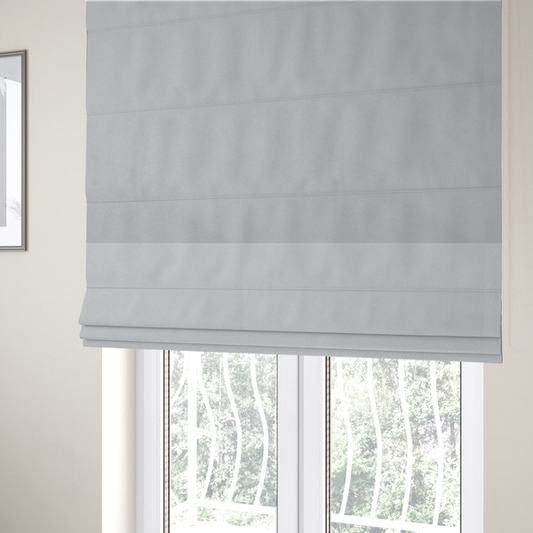 The fabric used to create these Roman blinds features a dense, plush pile with a soft matte finish in a bright, clean light grey. This high-performance upholstery material offers a luxurious texture and a specialized water-resistant coating for a modern, durable aesthetic.