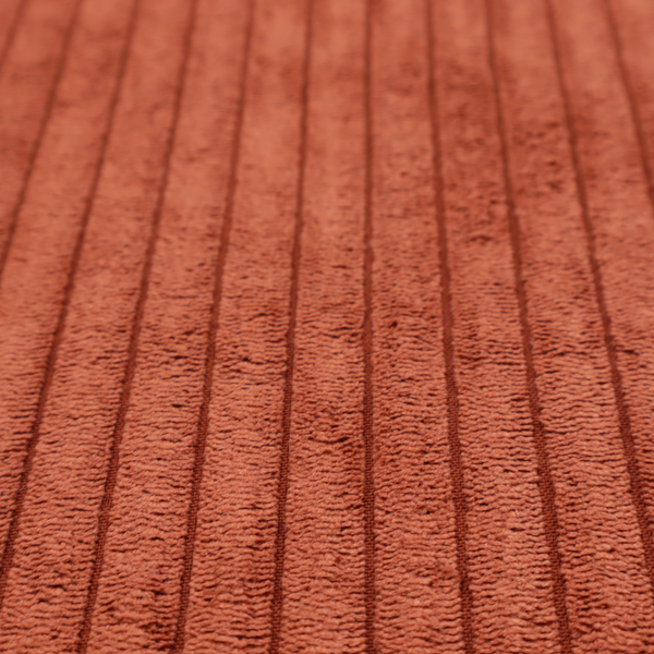 This fabric is a terracotta or burnt orange corduroy featuring a consistent vertical ribbed texture.