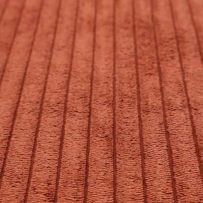 This fabric is a terracotta or burnt orange corduroy featuring a consistent vertical ribbed texture.