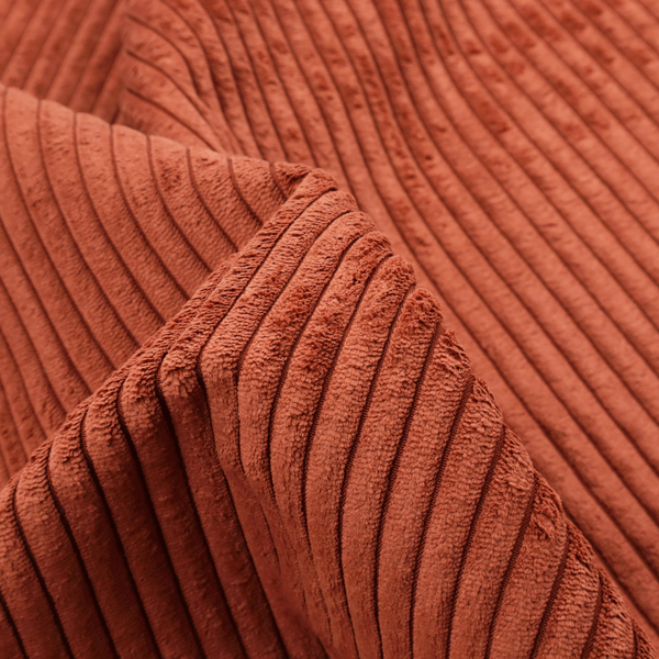 This fabric is a terracotta or burnt orange corduroy featuring a consistent vertical ribbed texture.