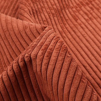 This fabric is a terracotta or burnt orange corduroy featuring a consistent vertical ribbed texture.