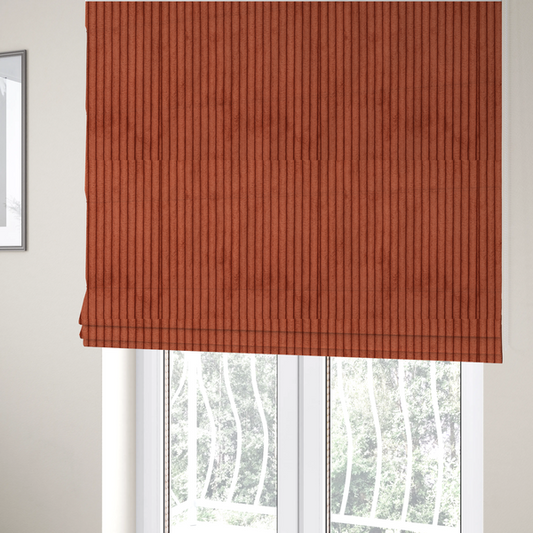 The fabric used to create these Roman blinds is a terracotta or burnt orange corduroy featuring a consistent vertical ribbed texture.