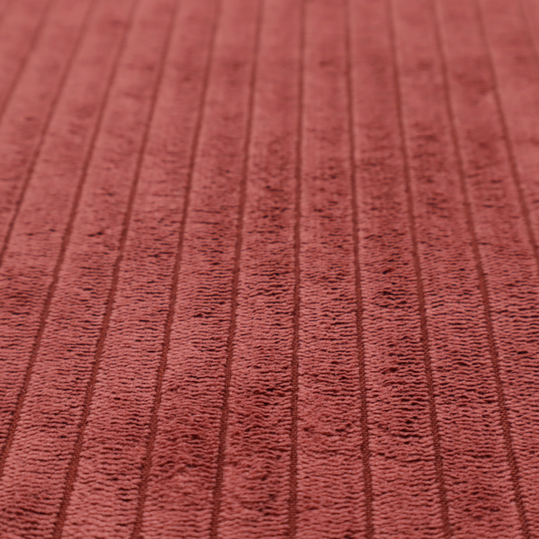This fabric is a brick red corduroy featuring a consistent vertical ribbed texture.