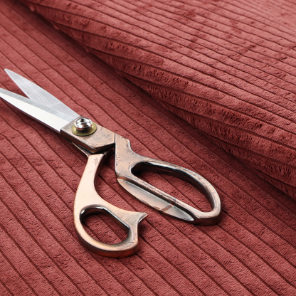 This fabric is a brick red corduroy featuring a consistent vertical ribbed texture.