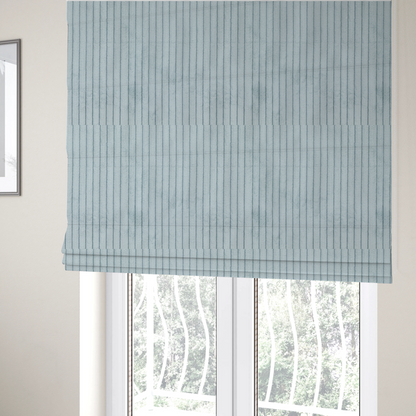 The fabric used to create these Roman blinds is a pale, icy blue corduroy featuring a consistent vertical ribbed texture.
