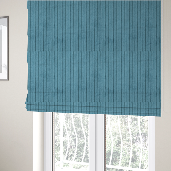 The fabric used to create these Roman blinds is a medium blue corduroy featuring a consistent vertical ribbed texture.