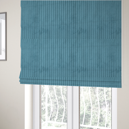 The fabric used to create these Roman blinds is a medium blue corduroy featuring a consistent vertical ribbed texture.