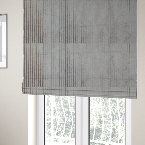 The fabric used to create these Roman blinds is a cool-toned, light grey or silver-grey corduroy featuring a consistent vertical ribbed texture.