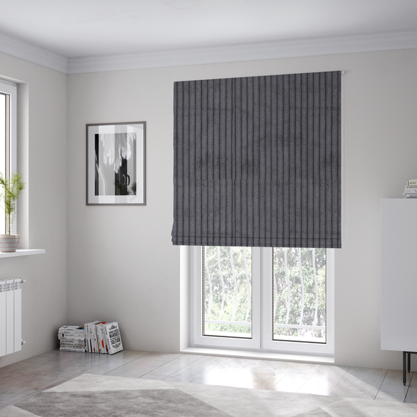 The fabric used to create these Roman blinds is a dark, cool-toned charcoal or slate-grey corduroy featuring a consistent vertical ribbed texture.