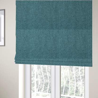 The fabric used to create these Roman blinds is a tightly woven fabric in a deep, cool-toned teal or seafoam blue, featuring a distinct, structured basket-weave pattern.