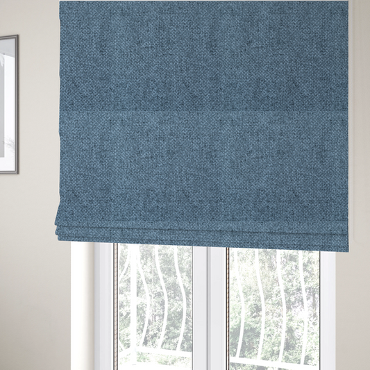 The fabric used to create these Roman blinds is a tightly woven fabric in a cool, muted slate blue, featuring a distinct, structured basket-weave pattern.