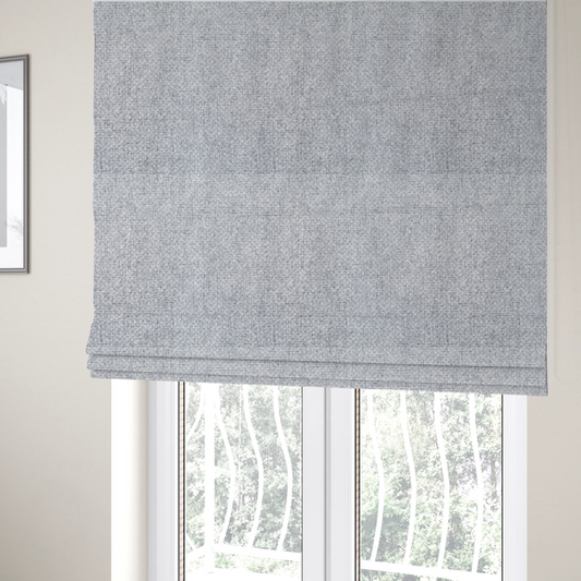 The fabric used to create these Roman blinds is a tightly woven fabric featuring a blend of white and cool-toned grey threads, creating a soft, light heathered effect with a distinct, structured basket-weave pattern.