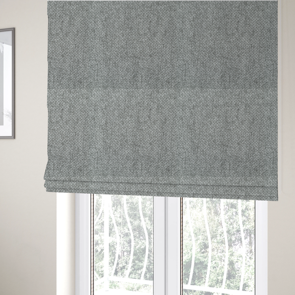 The fabric used to create these Roman blinds is a tight, woven texture with a neutral, monochromatic colour palette. The surface consists of a blend of light grey, charcoal, and white yarns interlocked in a repeating, small-scale geometric pattern.
