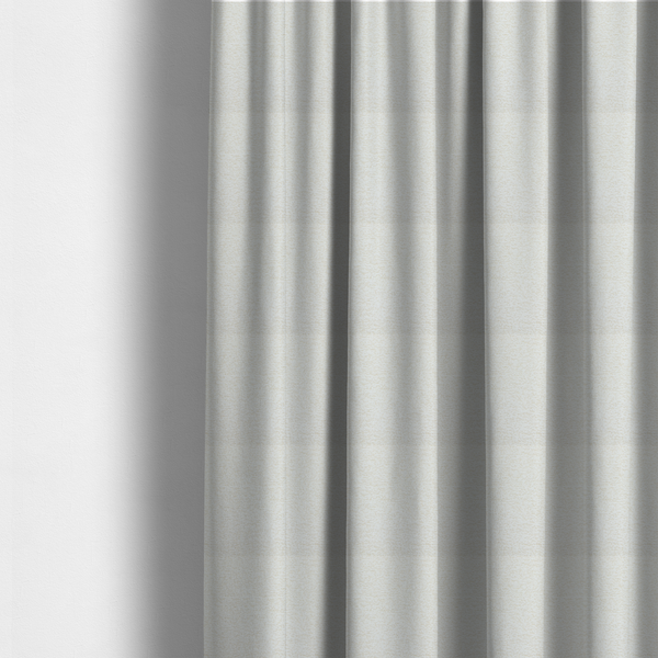 The fabric used to create these made-to-measure curtains is a  textured, off-white or cream-coloured weave. It has a bouclé-like or chunky, nubby appearance with a slightly irregular, multidimensional surface that gives it a cosy, organic, and tactile quality.