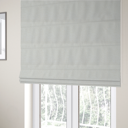 The fabric used to create these Roman blinds is a textured, off-white or cream-coloured weave. It has a bouclé-like or chunky, nubby appearance with a slightly irregular, multidimensional surface that gives it a cosy, organic, and tactile quality.