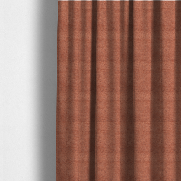 The fabric used to create these made-to-measure curtains is a vibrant, warm terracotta or rust-coloured weave. It features a dense, structured texture with horizontal ribbing and a consistent, slightly nubby finish that adds depth and character.