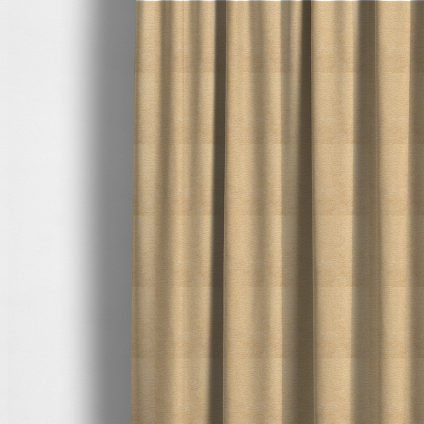 The fabric used to create these made-to-measure curtains is a warm, golden-beige weave with a sophisticated, textured finish. It is crafted with a dense, nubby construction that creates a subtle horizontal ribbing effect, providing both visual depth and a tactile, inviting feel.