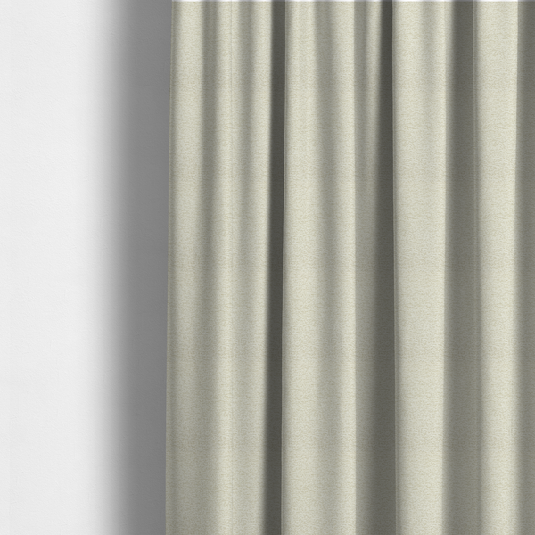 The fabric used to create these made-to-measure curtains is a light, creamy ivory weave with a refined, textured appearance. It is crafted with a dense, nubby construction that creates a subtle horizontal ribbing effect, providing both visual dimension and a soft, tactile quality.