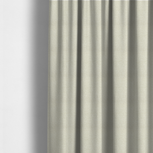 The fabric used to create these made-to-measure curtains is a light, creamy ivory weave with a refined, textured appearance. It is crafted with a dense, nubby construction that creates a subtle horizontal ribbing effect, providing both visual dimension and a soft, tactile quality.