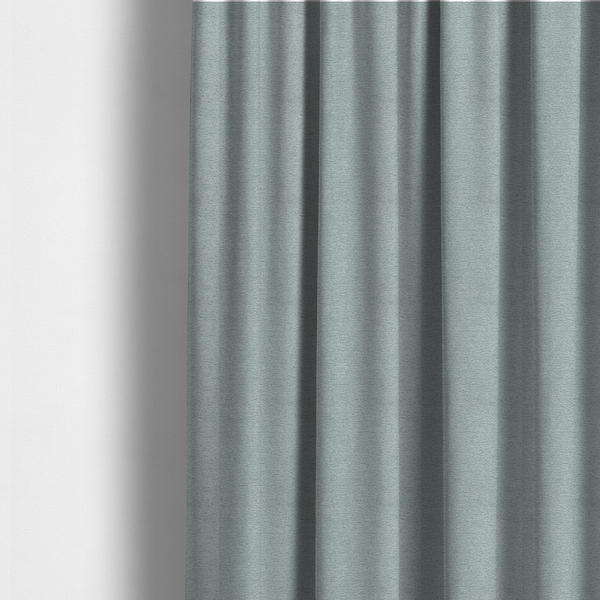 The fabric used to create these made-to-measure curtains is a sophisticated, cool-toned sage green weave with a refined, textured finish. It is crafted with a dense, nubby construction that creates a subtle horizontal ribbing effect, providing both visual dimension and a soft, inviting tactile quality.