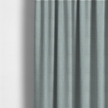The fabric used to create these made-to-measure curtains is a sophisticated, cool-toned sage green weave with a refined, textured finish. It is crafted with a dense, nubby construction that creates a subtle horizontal ribbing effect, providing both visual dimension and a soft, inviting tactile quality.