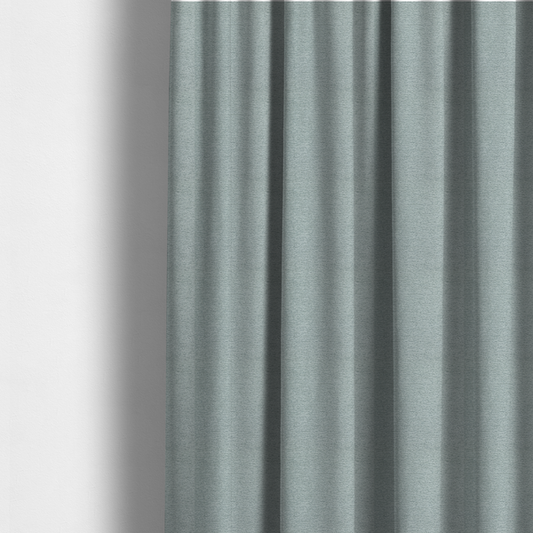 The fabric used to create these made-to-measure curtains is a sophisticated, cool-toned sage green weave with a refined, textured finish. It is crafted with a dense, nubby construction that creates a subtle horizontal ribbing effect, providing both visual dimension and a soft, inviting tactile quality.