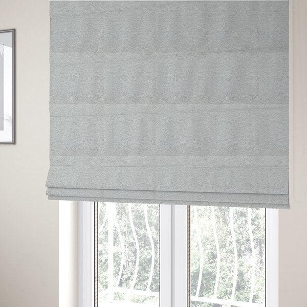 The fabric used to create these Roman blinds is a clean, contemporary light-grey and white weave. It is crafted with a dense, nubby construction that creates a subtle horizontal ribbing effect, providing both visual dimension and a soft, tactile quality.